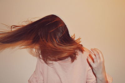 Woman with tousled hair standing against wall