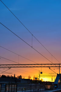 Power lines against clear sky at sunset