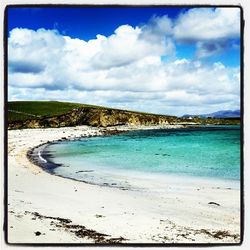 Scenic view of beach against cloudy sky