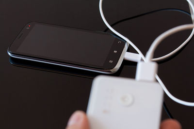 Cropped hand holding portable charger against black background