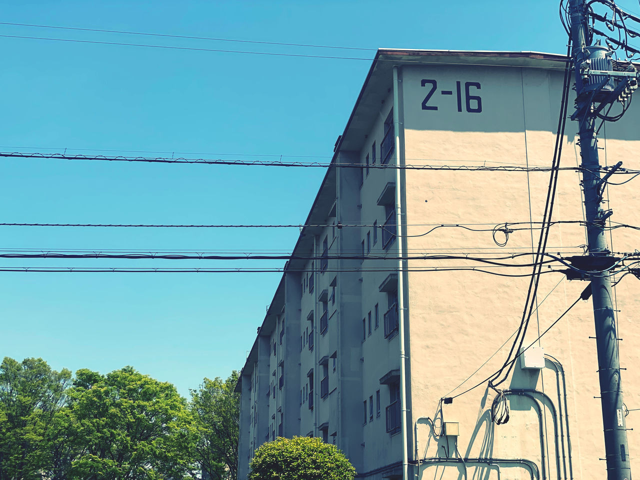 LOW ANGLE VIEW OF TELEPHONE POLE AGAINST BUILDING