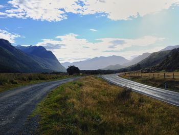 Road leading towards mountains against sky