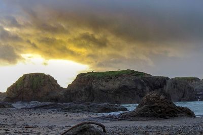 Rock formation by sea against sky