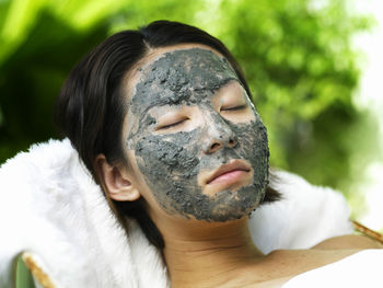 Close-up of young woman with facial mask relaxing at spa