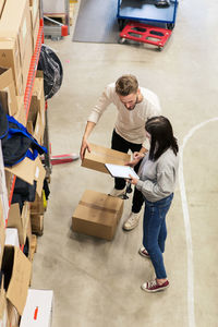 High angle view of colleagues discussing over cardboard box in industry