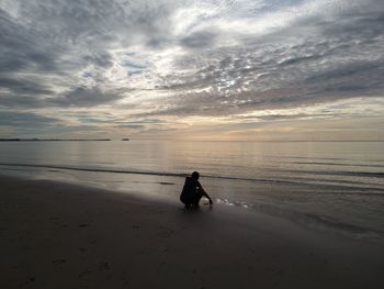 Man on beach against sky during sunset