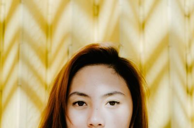 Close-up portrait of woman against yellow background