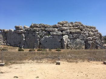 Built structure on field against clear blue sky