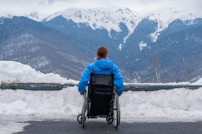 Rear view of woman standing on snowcapped mountain