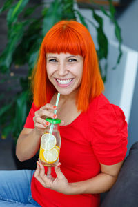 Portrait of smiling young woman drinking drink