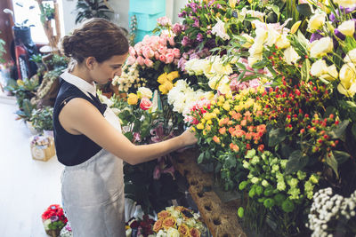 Side view of female owner arranging roses at shop