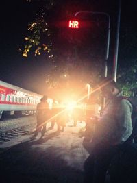 People walking on illuminated railroad tracks at night