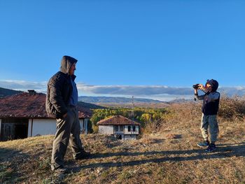 Rear view of man standing on mountain against clear sky