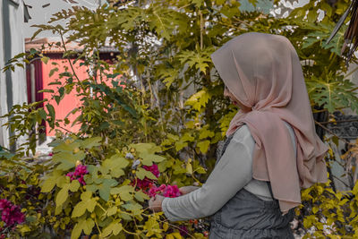 Midsection of woman by flowering plants against trees