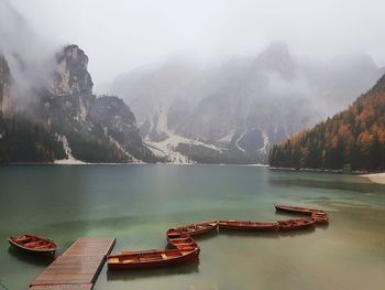 Boats moored in lake against mountains during winter