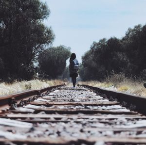 Rear view of man walking on railroad track