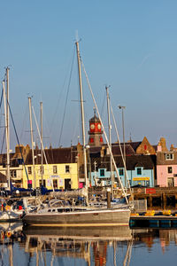 Boats moored at harbor against sky