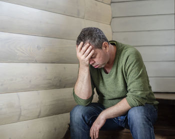 Depressed mature man with head in hand sitting at home