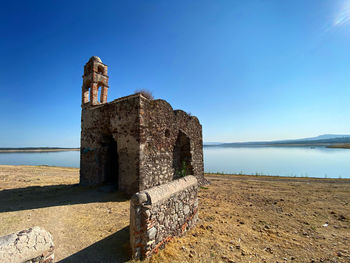 Old castle on beach against clear blue sky