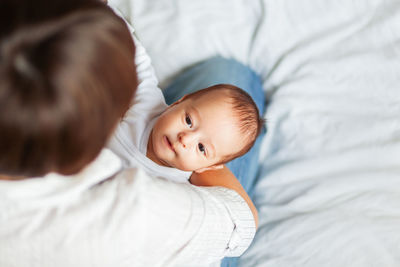 High angle view of mother holding baby on bed