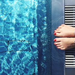 Low section of woman standing at poolside