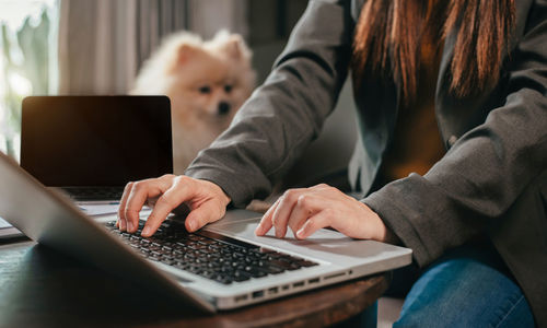 Midsection of woman using mobile phone while sitting on table