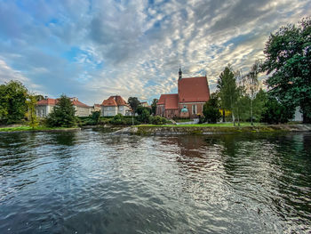 Buildings by lake against sky