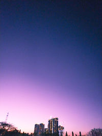 Buildings in city against clear blue sky