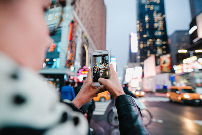 Man photographing woman using smart phone on street