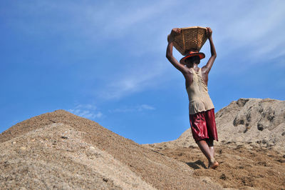 Woman wearing hat standing on land against sky