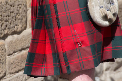 Cropped image of person wearing traditional clothing while standing against stone wall