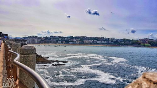 Cityscape by sea against sky