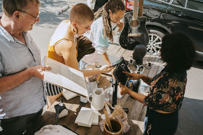 High angle view of owner processing online payment of female customer at flea market