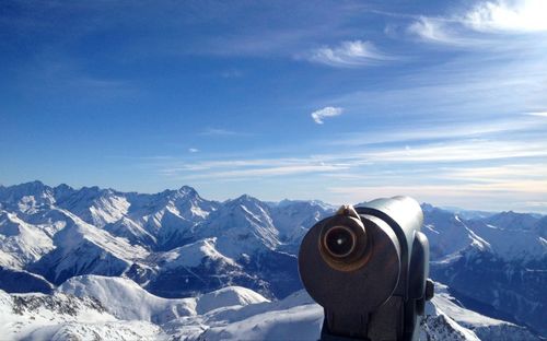 Coin-operated binocular against snow covered mountains