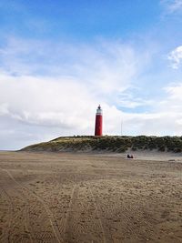 Lighthouse on beach against sky