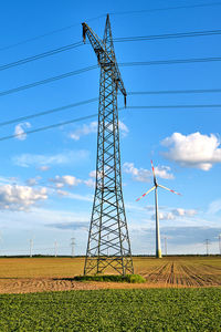 Low angle view of electricity pylon on field against sky