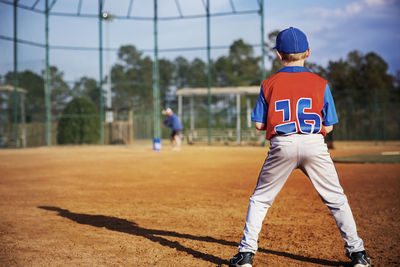 Rear view of boy playing baseball on field