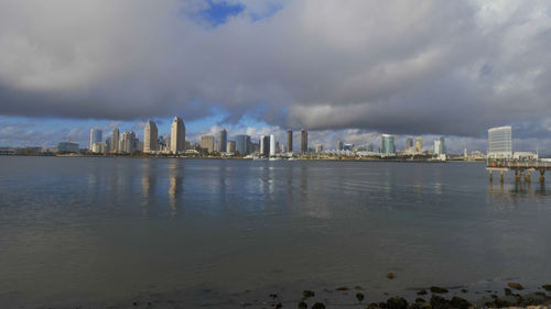 Sea by buildings against sky in city