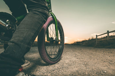 Midsection of man riding bicycle against sky during sunset