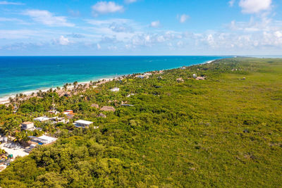 Aerial tulum coastline by the beach with a magical caribbean sea and small huts by the coast.