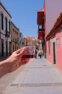 Mano masculina con copa de vino en avenida urbana. male hand with red wine glass on urban avenue