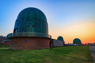 Built structure on field against sky during sunset