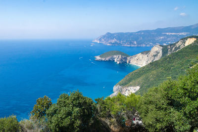 Scenic view of sea and mountains against clear blue sky