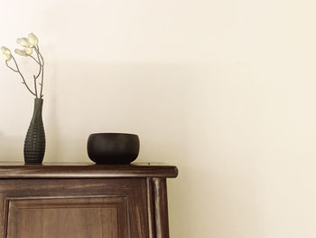 Close-up of vase on table against wall at home