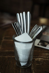 Close-up of spoons with tissue paper in glass on table