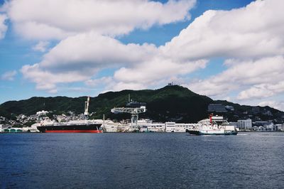 Boats sailing in sea against cloudy sky