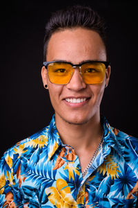 Portrait of young man wearing sunglasses against black background