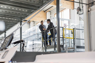 Two businessmen talking in modern factory