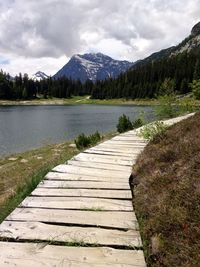 Footpath by lake against sky