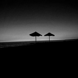 Silhouette lifeguard hut on beach against clear sky
